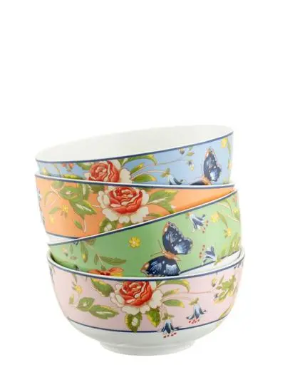 A stack of three colorful ceramic bowls with floral and butterfly patterns, each in different pastel shades of pink, orange, and blue, isolated on a white background.